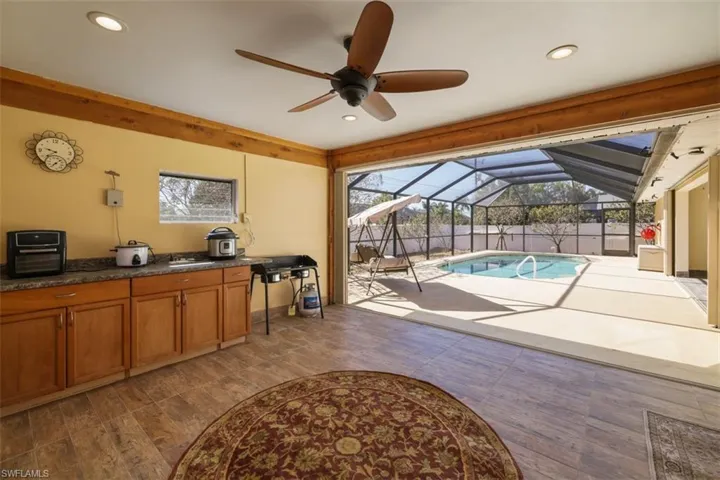 View of pool with a lanai, area for grilling, a sunroom, and patio surround