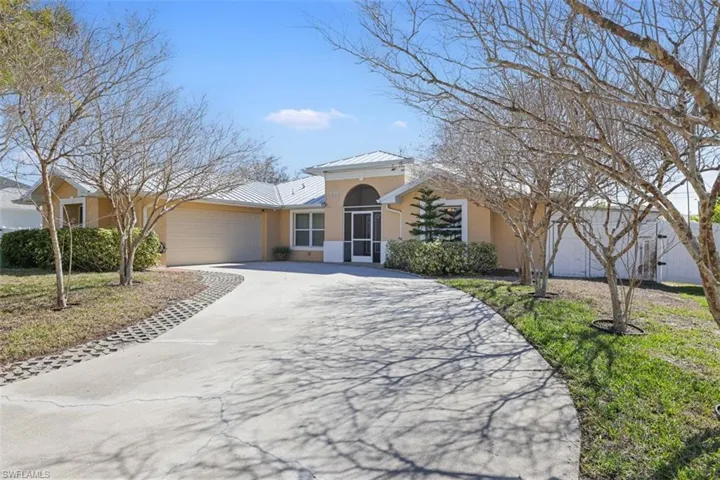 View of front of house featuring stucco siding, driveway, a garage, and a standing seam roof