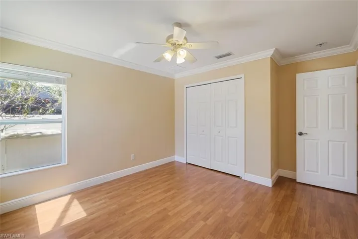 Unfurnished bedroom with ornamental molding, light wood-style flooring, ceiling fan, and a closet