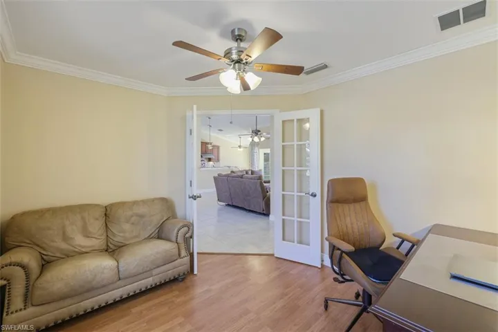 Home office featuring ornamental molding, french doors, light wood finished floors, and a ceiling fan