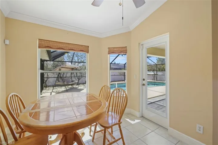 Tiled dining area with a sunroom, a ceiling fan, and ornamental molding