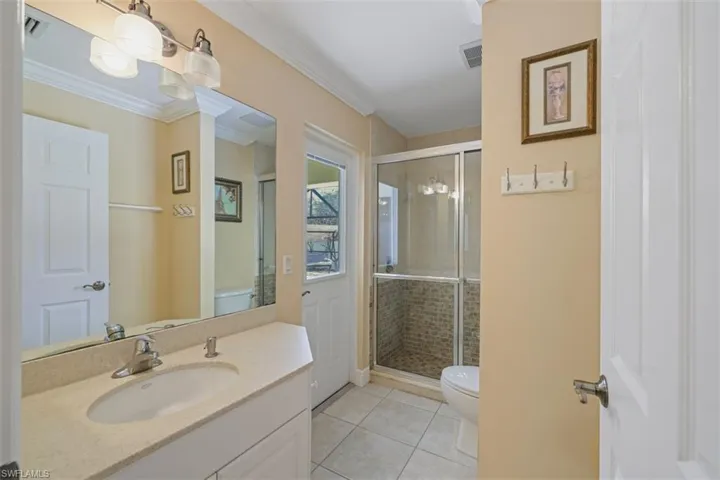 Full bathroom with a stall shower, vanity, light tile patterned floors, and ornamental molding