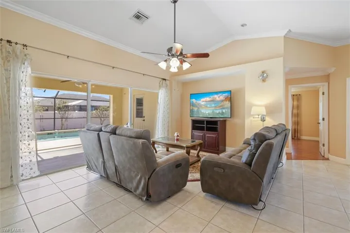 Living area with a sunroom, crown molding, ceiling fan, lofted ceiling, and light tile patterned floors