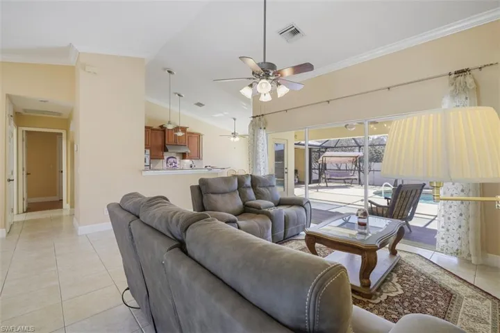 Living room with crown molding, ceiling fan, lofted ceiling, and light tile patterned floors