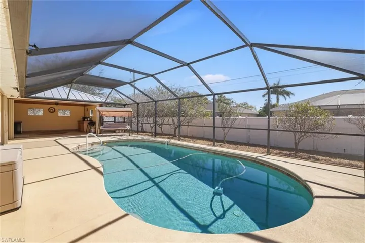 View of pool with glass enclosure, a fenced backyard, a sunroom, and patio surround
