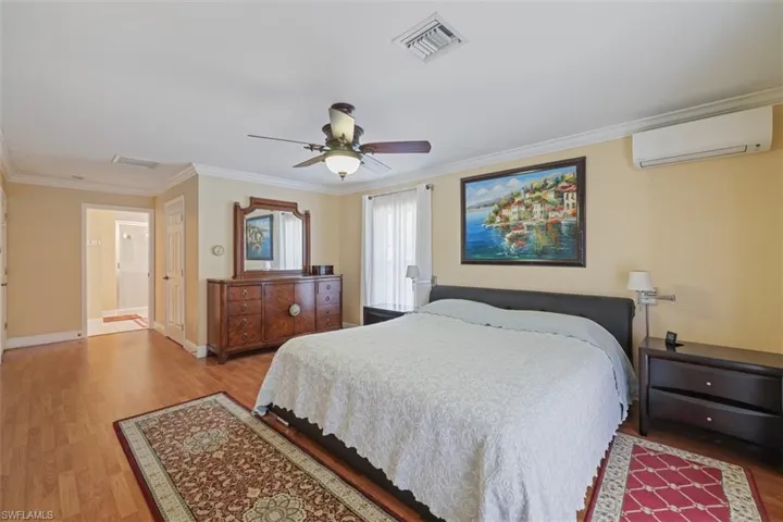 Bedroom featuring light wood-type flooring, ornamental molding, ceiling fan, and ensuite bath