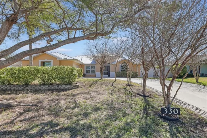 View of front of home with stucco siding, driveway, a metal roof, and a front yard