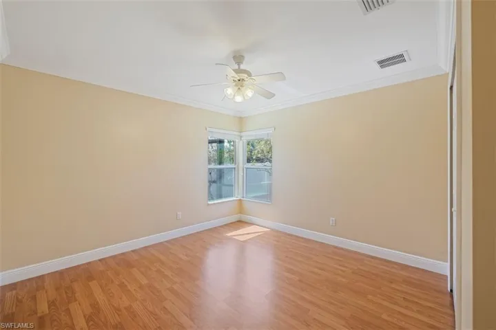 Unfurnished room with ornamental molding, light wood-style flooring, and ceiling fan