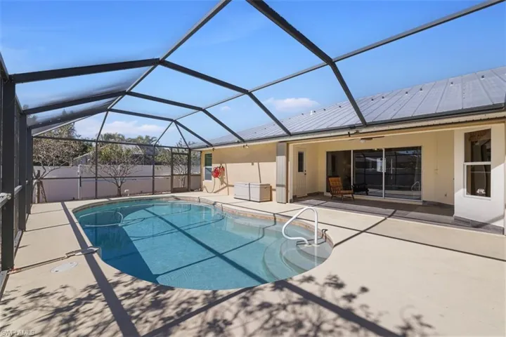 View of pool with a sunroom, patio surround, and glass enclosure