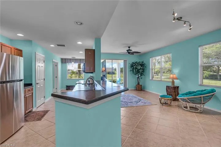 Kitchen featuring stainless steel fridge, sink, track lighting, ceiling fan, and light tile floors