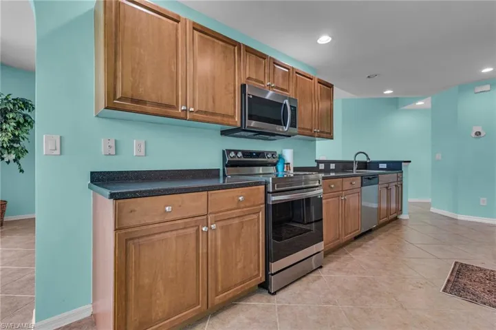 Kitchen with sink, light tile flooring, and appliances with stainless steel finishes