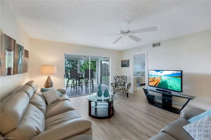 Living room featuring ceiling fan, a textured ceiling, and light hardwood / wood-style flooring