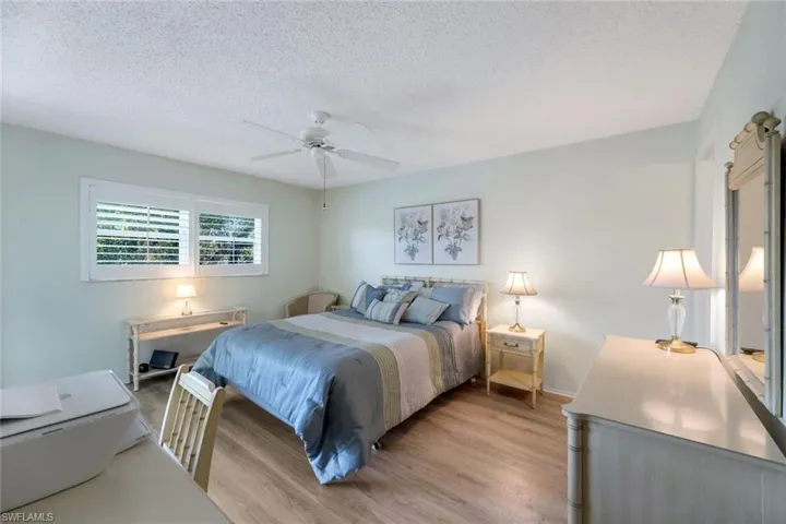 Bedroom with ceiling fan, a textured ceiling, and light wood-type flooring