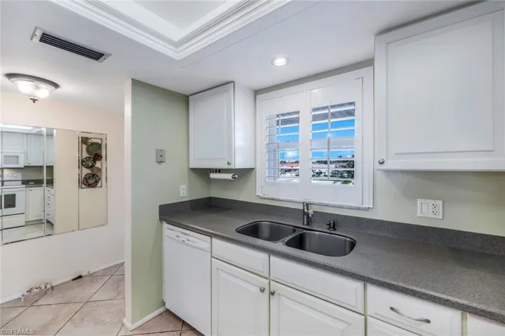 Kitchen featuring white cabinetry, sink, light tile patterned floors, and white appliances