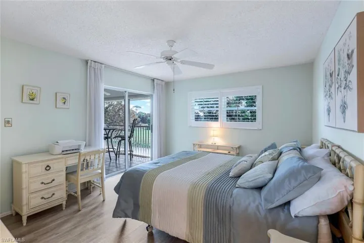 Bedroom with access to outside, multiple windows, wood-type flooring, and ceiling fan
