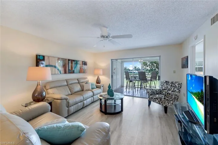 Living room featuring light hardwood / wood-style floors, a textured ceiling, and ceiling fan
