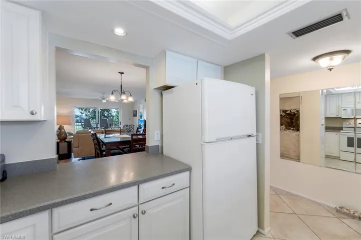 Kitchen featuring white cabinets, light tile patterned floors, and white appliances