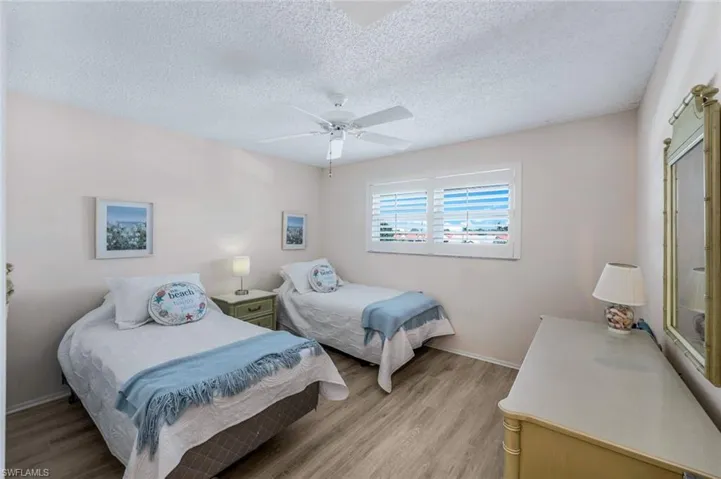 Bedroom with light hardwood / wood-style flooring, a textured ceiling, and ceiling fan
