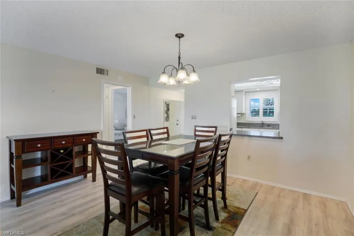 Dining room featuring a notable chandelier, a textured ceiling, and light hardwood / wood-style floors