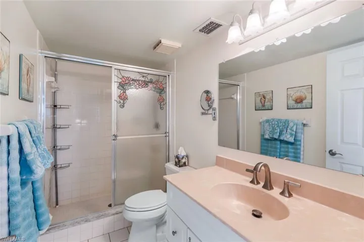 Bathroom with vanity, toilet, tile patterned floors, and a shower with shower door