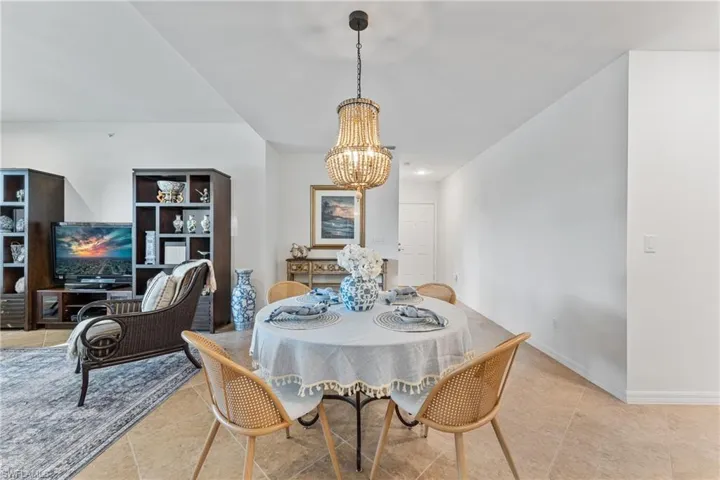 Tiled dining room with a chandelier and baseboards