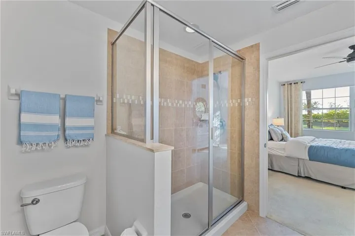 Full bath with a stall shower, connected bathroom, ceiling fan, light colored carpet, and light tile patterned flooring