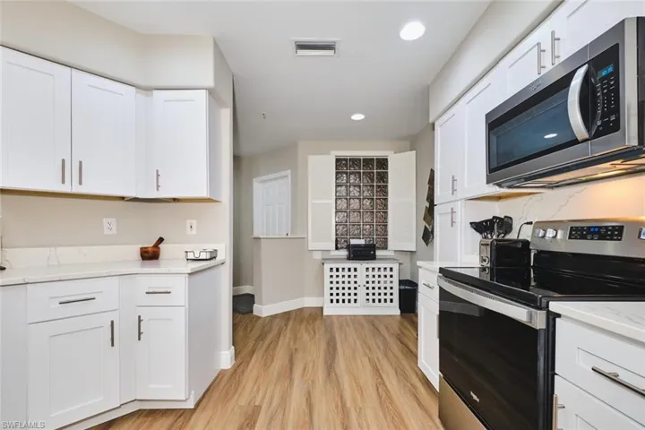 Kitchen featuring appliances with stainless steel finishes, recessed lighting, white cabinetry, and light stone countertops