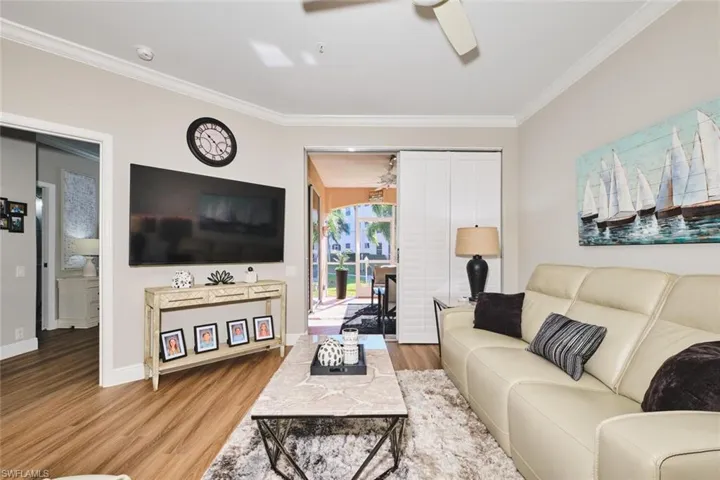 Living area with light wood-style flooring, crown molding, and ceiling fan