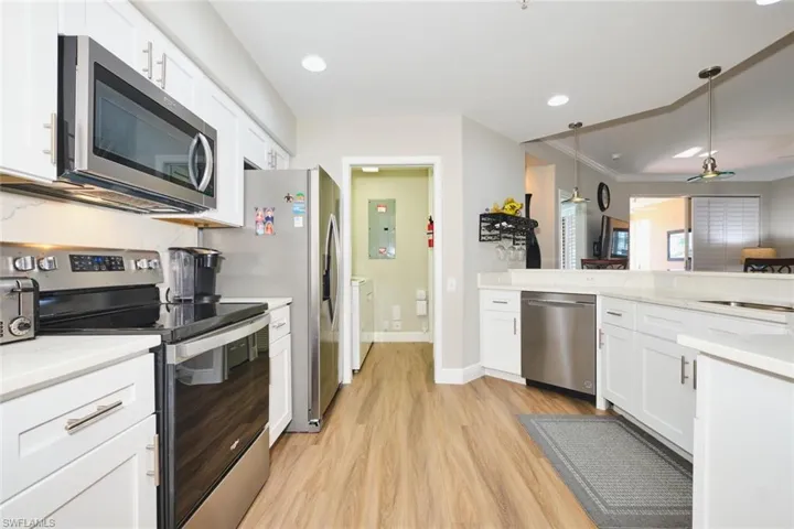 Kitchen featuring appliances with stainless steel finishes, white cabinetry, hanging light fixtures, recessed lighting, and light stone countertops