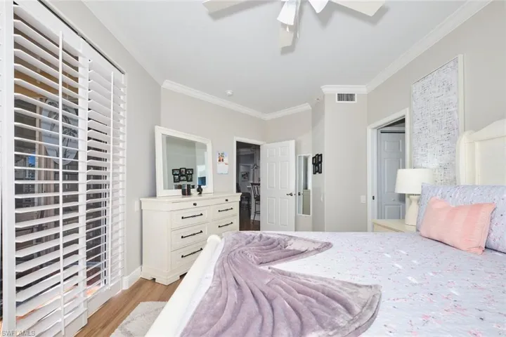 Bedroom featuring crown molding, light wood finished floors, a ceiling fan, and a closet