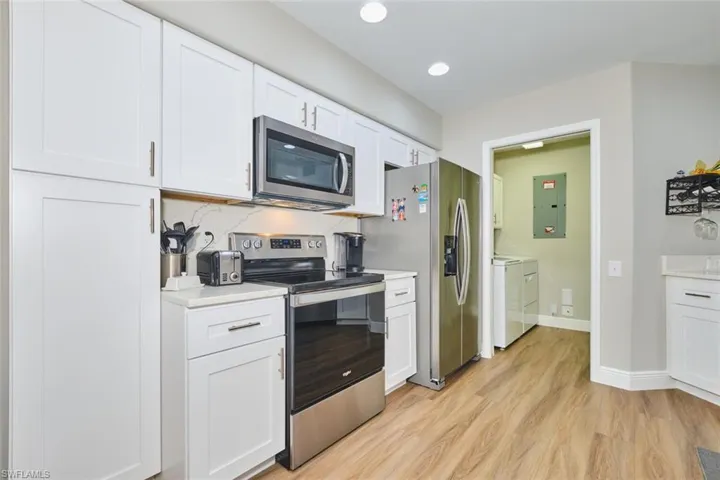 Kitchen with appliances with stainless steel finishes, white cabinetry, independent washer and dryer, backsplash, and electric panel