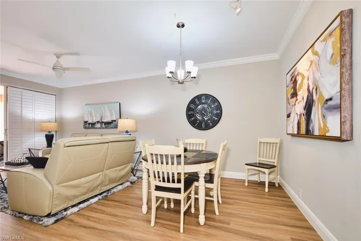 Dining area featuring crown molding, ceiling fan, light wood-style floors, and a chandelier