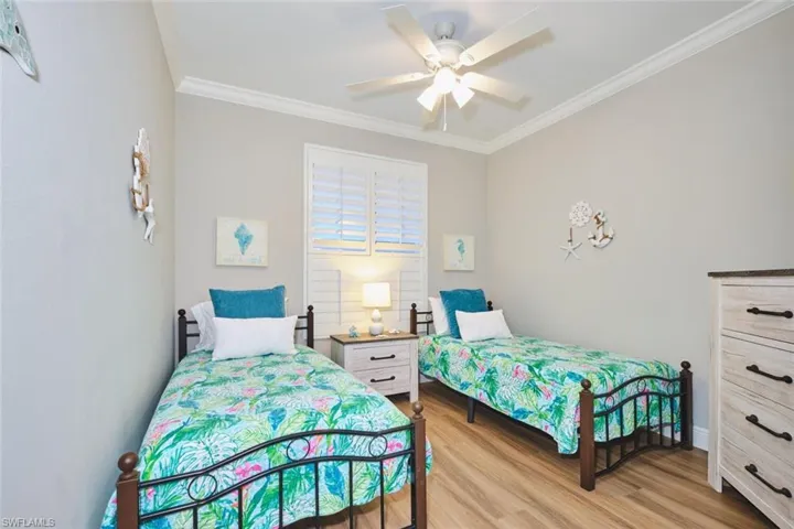 Bedroom featuring crown molding, light wood-type flooring, and a ceiling fan