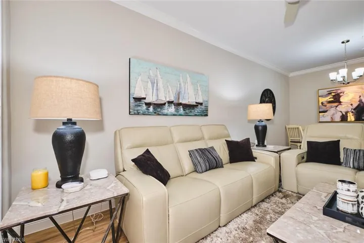 Living area featuring ornamental molding, a chandelier, a ceiling fan, and wood finished floors