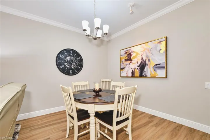 Dining space with crown molding, a chandelier, and light wood-style floors