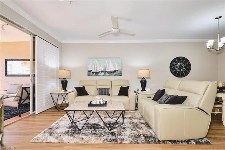 Living room featuring ornamental molding, wood finished floors, and a chandelier