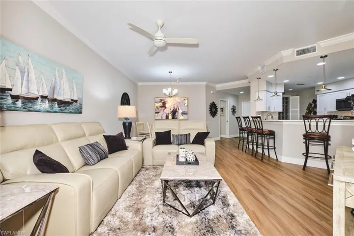 Living area featuring ornamental molding, ceiling fan, a chandelier, and light wood-style floors