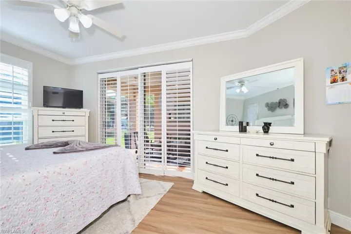 Bedroom with crown molding, access to outside, a ceiling fan, light wood-type flooring, and multiple windows