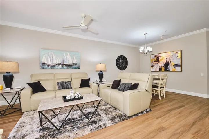Living area featuring ornamental molding, wood finished floors, a chandelier, and ceiling fan