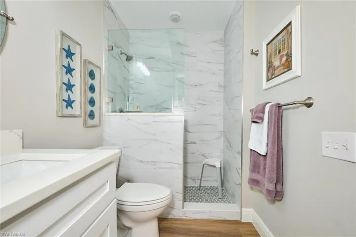 Full bathroom with vanity, a marble finish shower, and light wood-style flooring