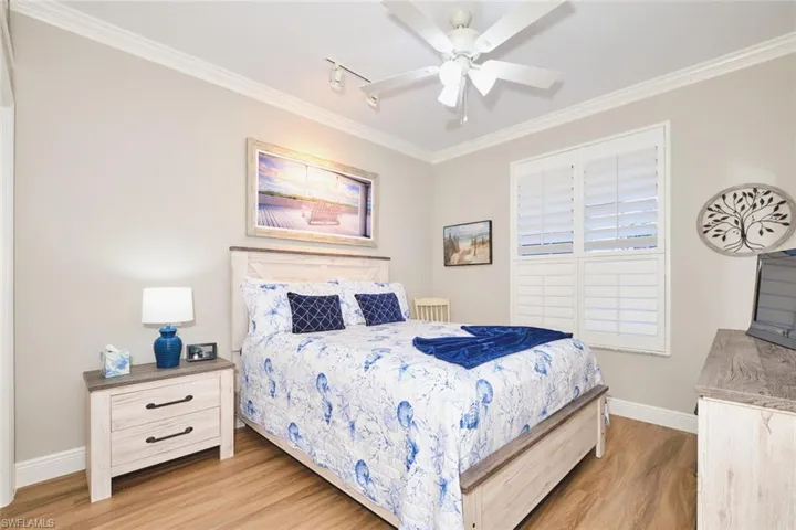 Bedroom featuring ornamental molding, light wood-style flooring, ceiling fan, and rail lighting
