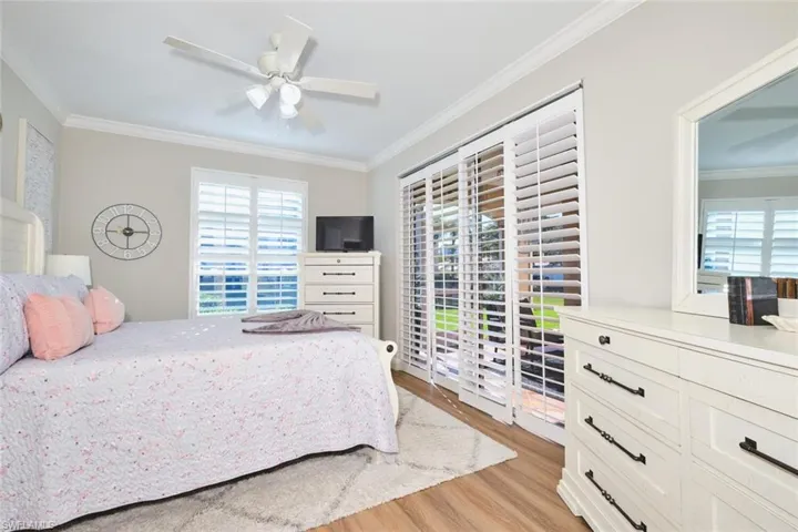 Bedroom featuring ornamental molding, light wood finished floors, ceiling fan, and access to exterior