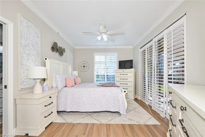Bedroom with crown molding, light wood-style floors, and ceiling fan