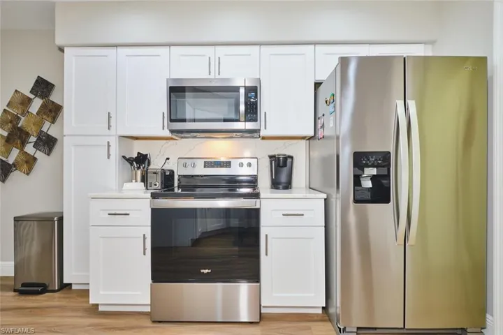 Kitchen with stainless steel appliances, white cabinets, tasteful backsplash, and light wood-type flooring