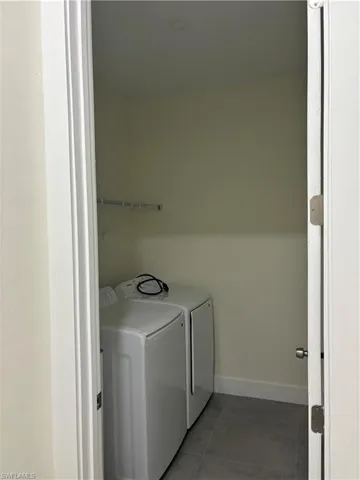 Laundry area featuring independent washer and dryer and dark tile patterned floors