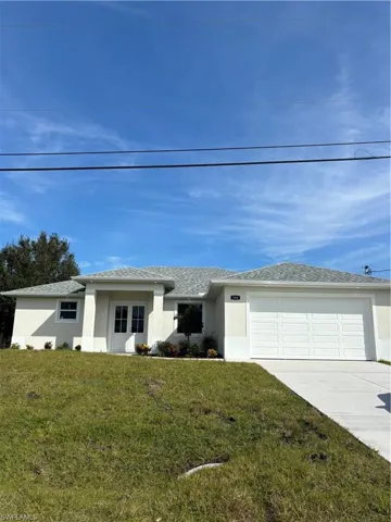 View of front of home featuring stucco siding, a front yard, concrete driveway, and an attached garage