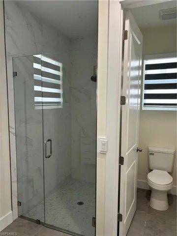 Full bathroom with plenty of natural light, a marble finish shower, and light tile patterned flooring
