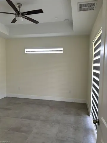 Empty room featuring a raised ceiling and a ceiling fan