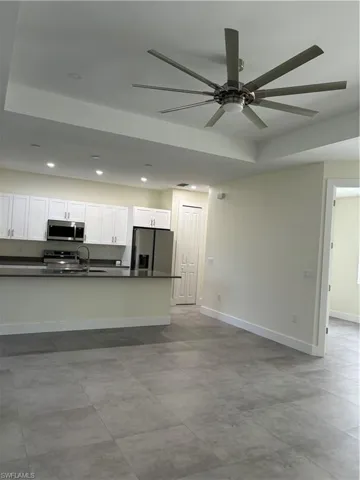 Kitchen featuring dark countertops, ceiling fan, white cabinetry, recessed lighting, and stove