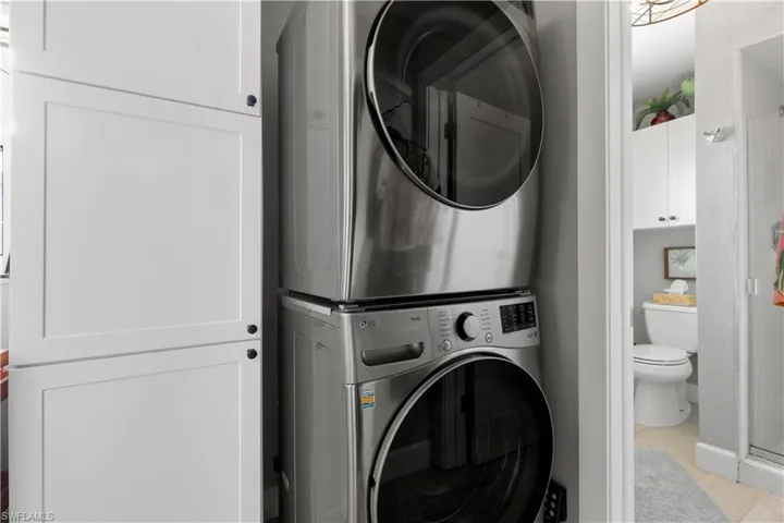 In home Laundry area with stacked washer and clothes dryer plus storage.